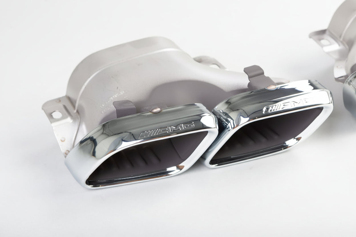 Chrome car exhaust pipes on a white background with 'Mercedes-Benz' branding.